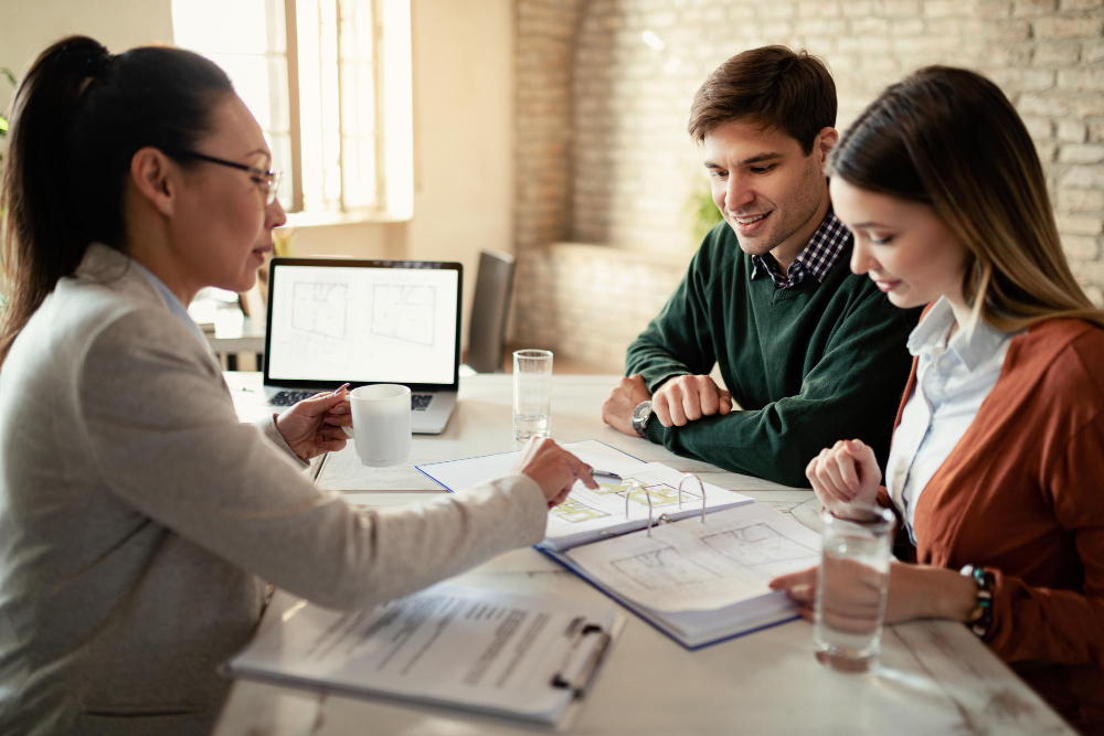 smiling-couple-insurance-agent-going-through-real-estate-plans-during-meeting-office-focus-is-man